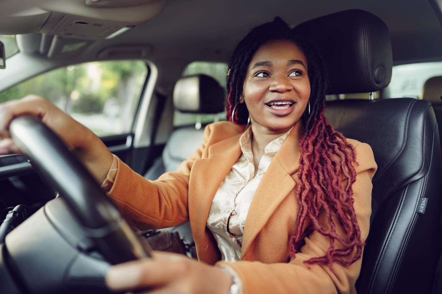 Driver in an orange coat laughing at the wheel